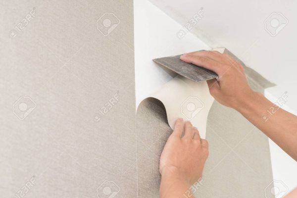 Handyman putting up wallpaper on the white walls